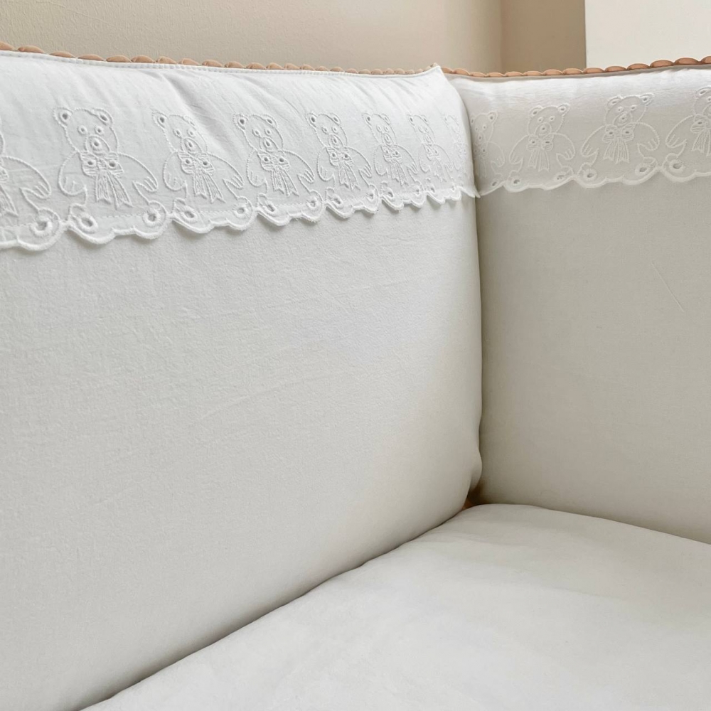 Detailaufnahme des Babybett-Bumpers mit einem charmanten, gestickten Bärenmuster in Milchweiß, das dem Set einen niedlichen, einzigartigen Touch verleiht