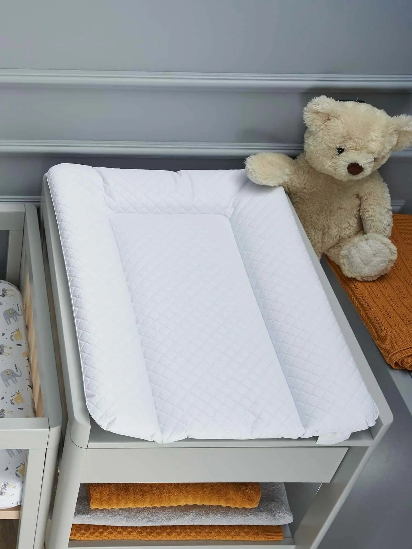 Veres PureComfort Weiche Wickelauflage 50*70 cm auf Wickeltisch mit einem Teddy und Textilien im Hintergrund