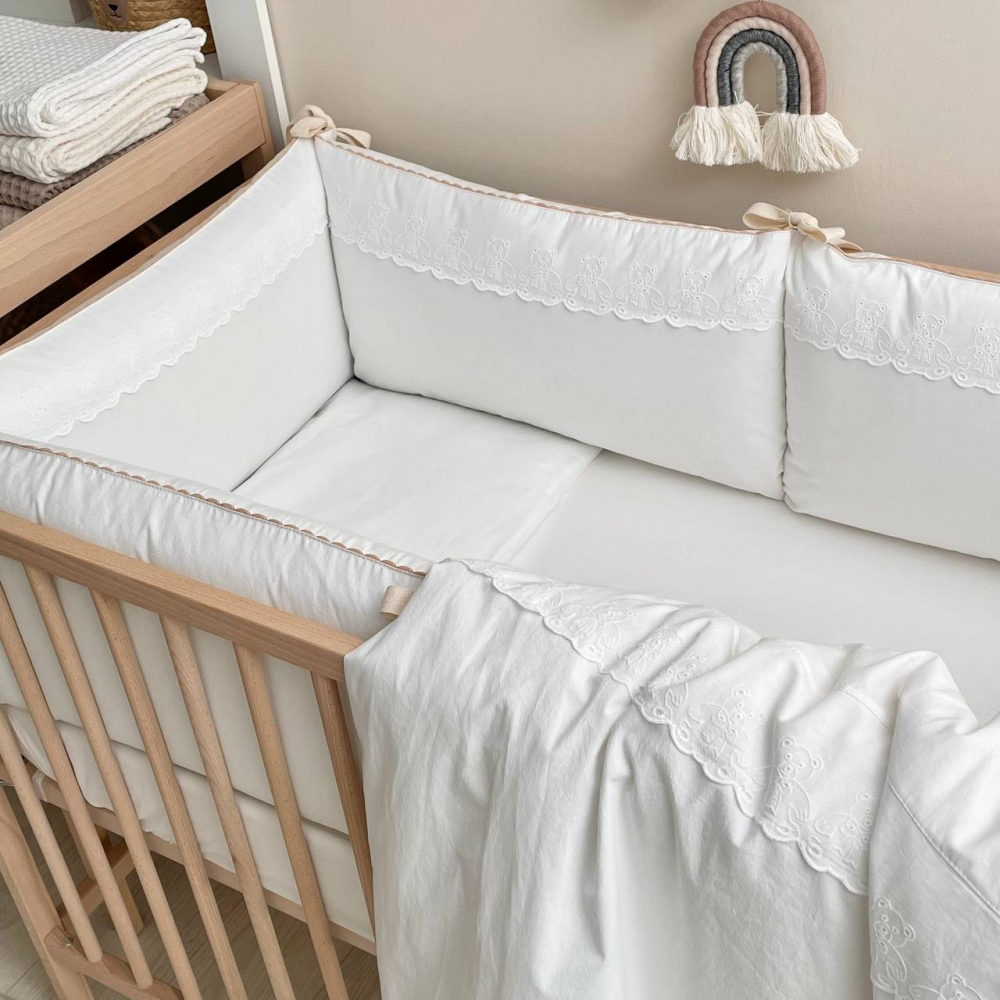 Babybett mit Bettwäsche-Set in Milchweiß, eingerahmt von sanften, neutralen Tönen im modernen Kinderzimmer. Die süßen Teddy-Details fügen sich harmonisch in die gemütliche und stilvolle Atmosphäre ein